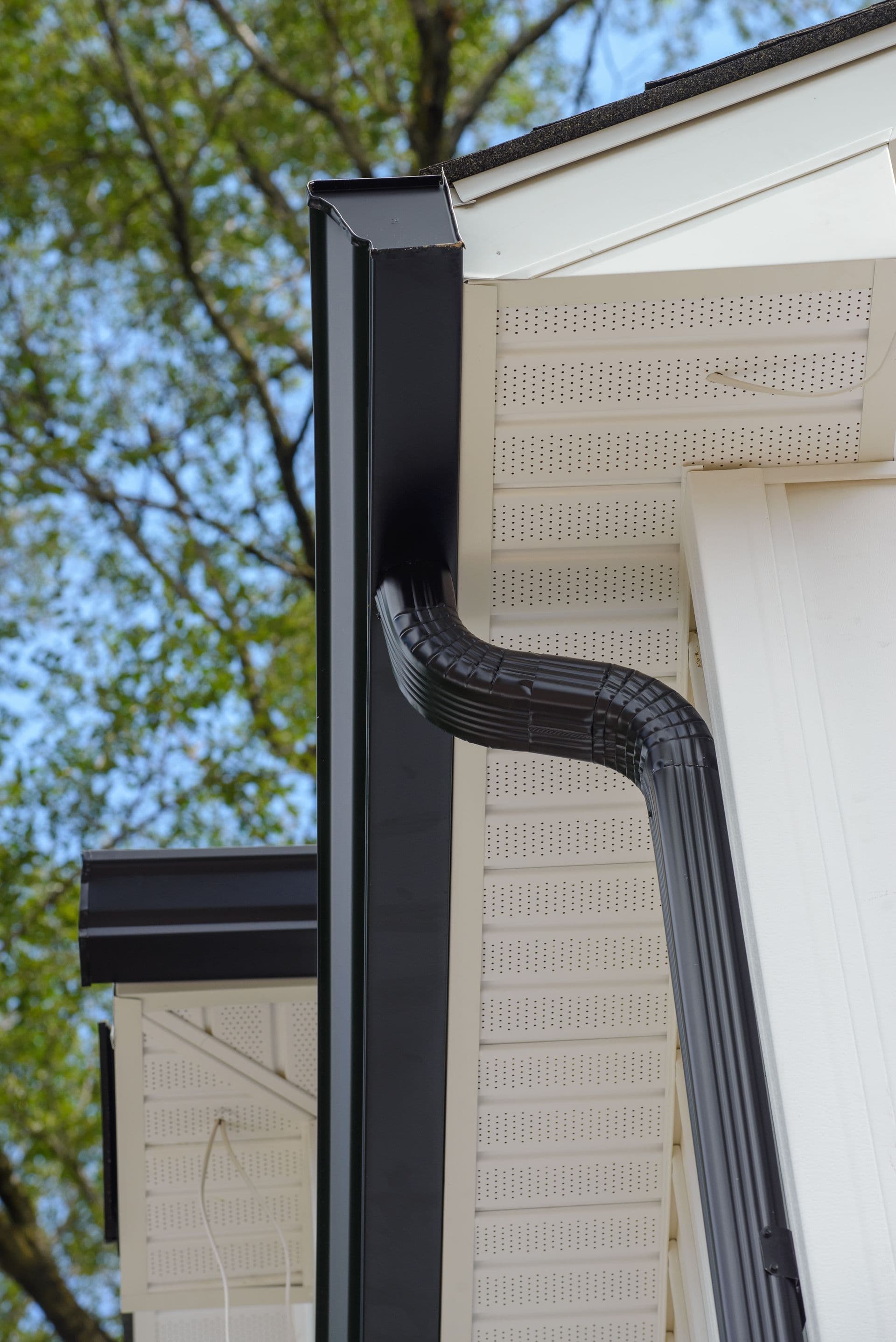 A close up of a black gutter on the side of a house
