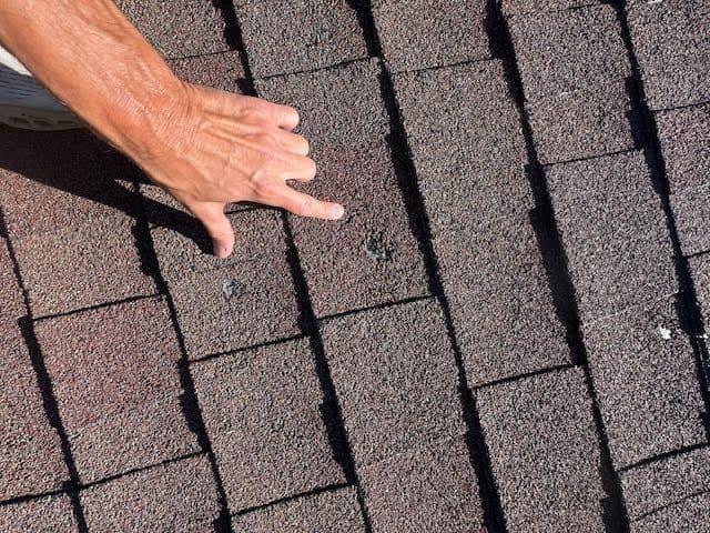 A person is pointing at a hole in a roof.